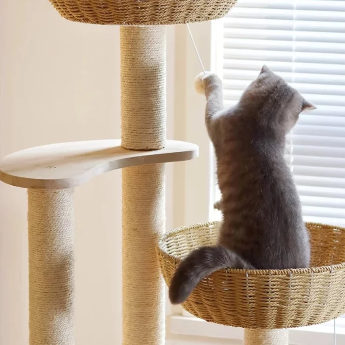 A cat is playing with this little ball of this wood cat tower.