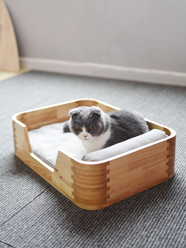 A fold-eared cat is lying on a solid wood cat bed.